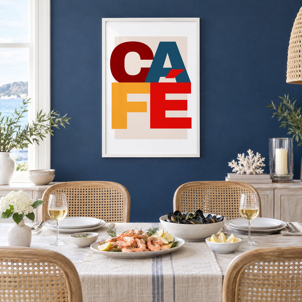 CA FÉ color block letters print in a white frame on a navy wall above a dining table set with shrimp and mussels