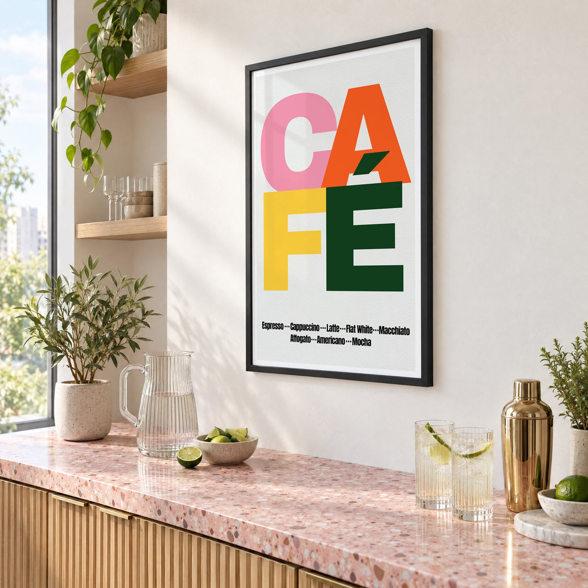 CAFÉ color block coffee menu print in a black frame above a pink terrazzo cocktail counter with limes, seen at an angle