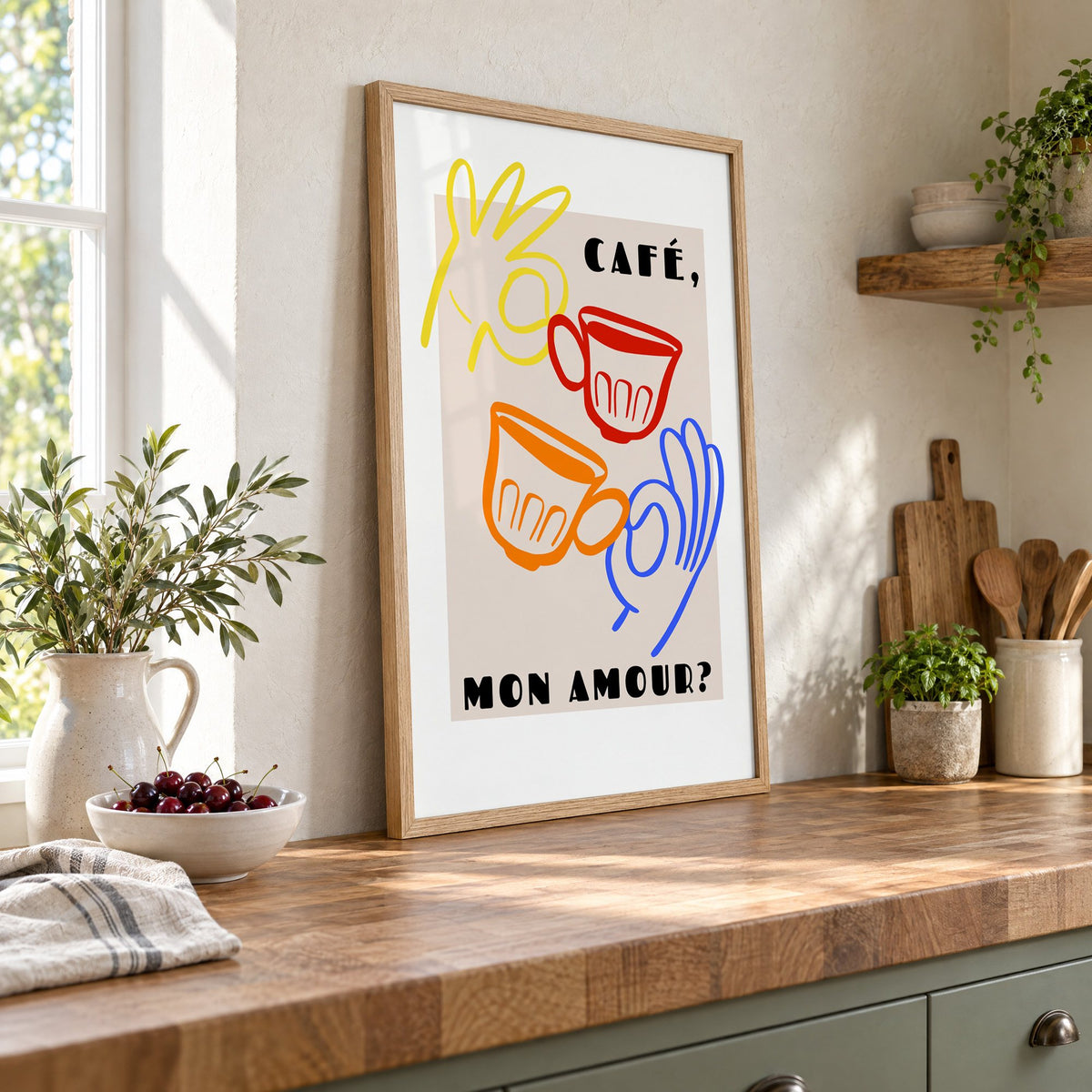 Café mon amour yellow hand beige print in an oak frame leaning on a butcher block island beside a bowl of cherries