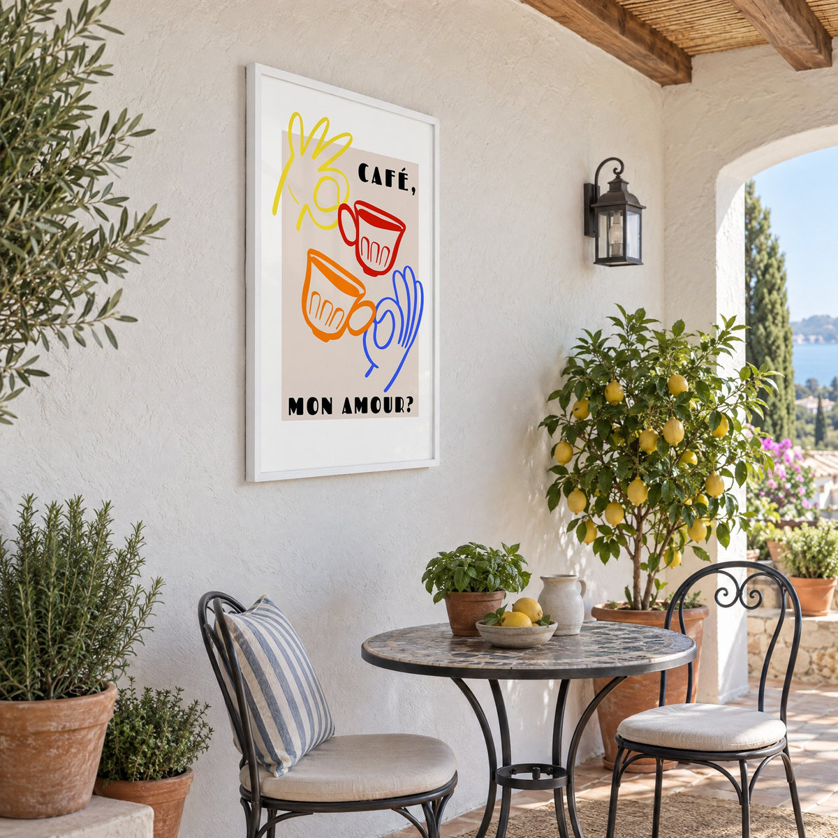 Café mon amour yellow hand beige print in a white frame on a sunny patio wall beside a potted lemon tree