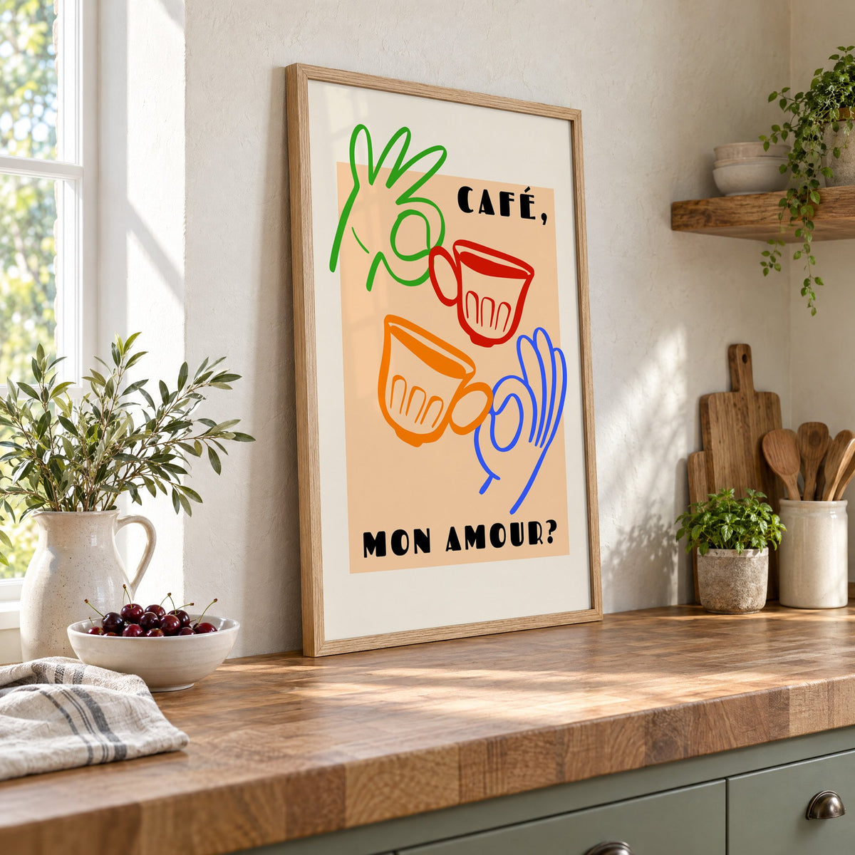 Café mon amour peach coffee cups print in an oak frame leaning on a butcher block island beside a bowl of cherries
