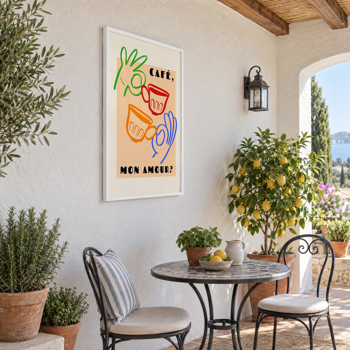 Café mon amour peach coffee cups print in a white frame on a sunny patio wall beside a potted lemon tree