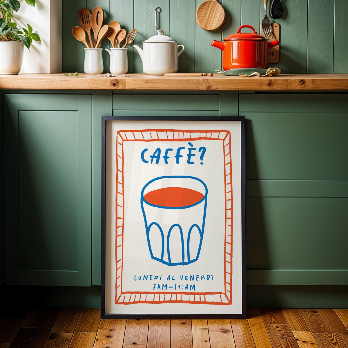 Caffe cobalt glass print in a black frame against sage green kitchen cabinets