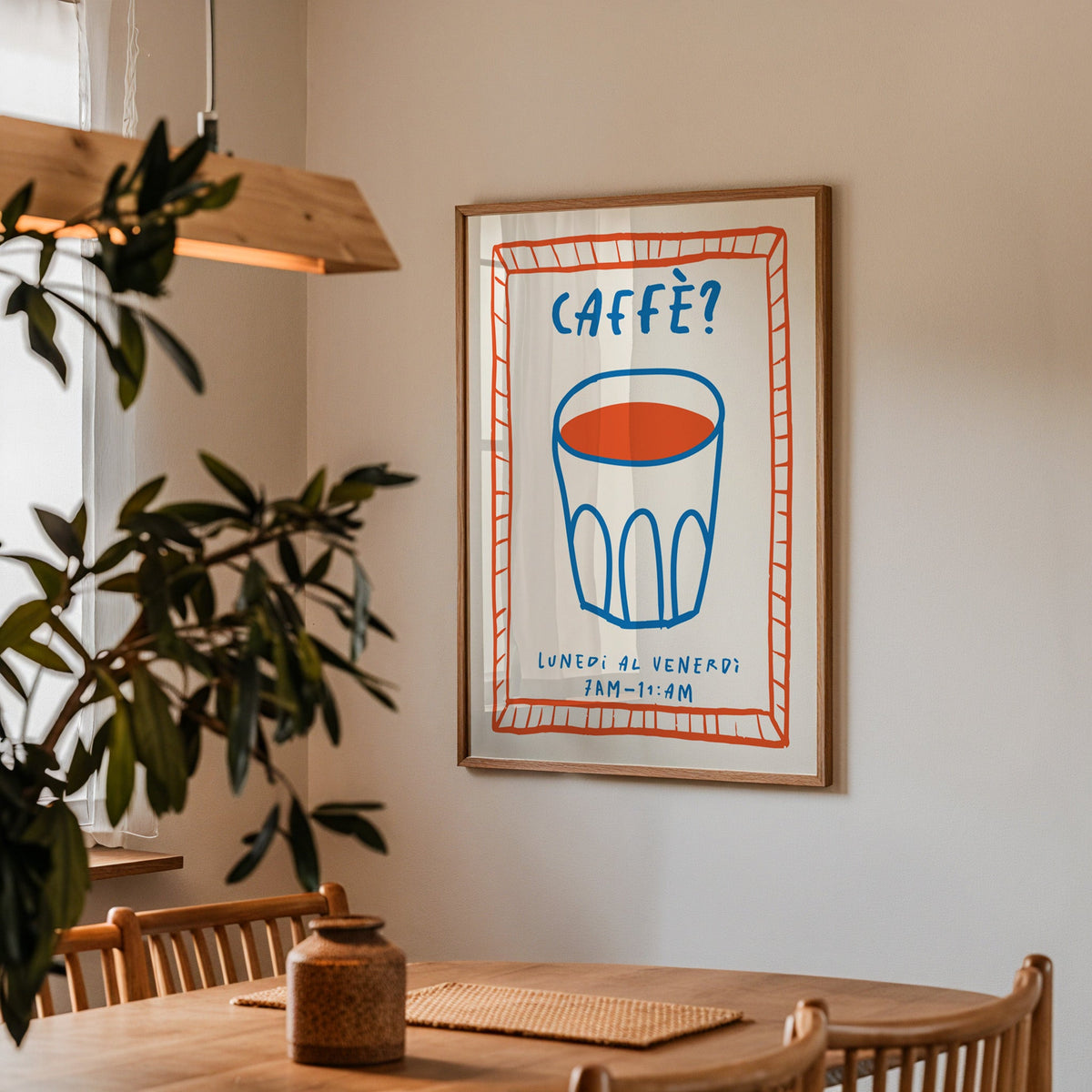 Caffe cobalt glass print in a walnut frame above a dining table by an olive tree