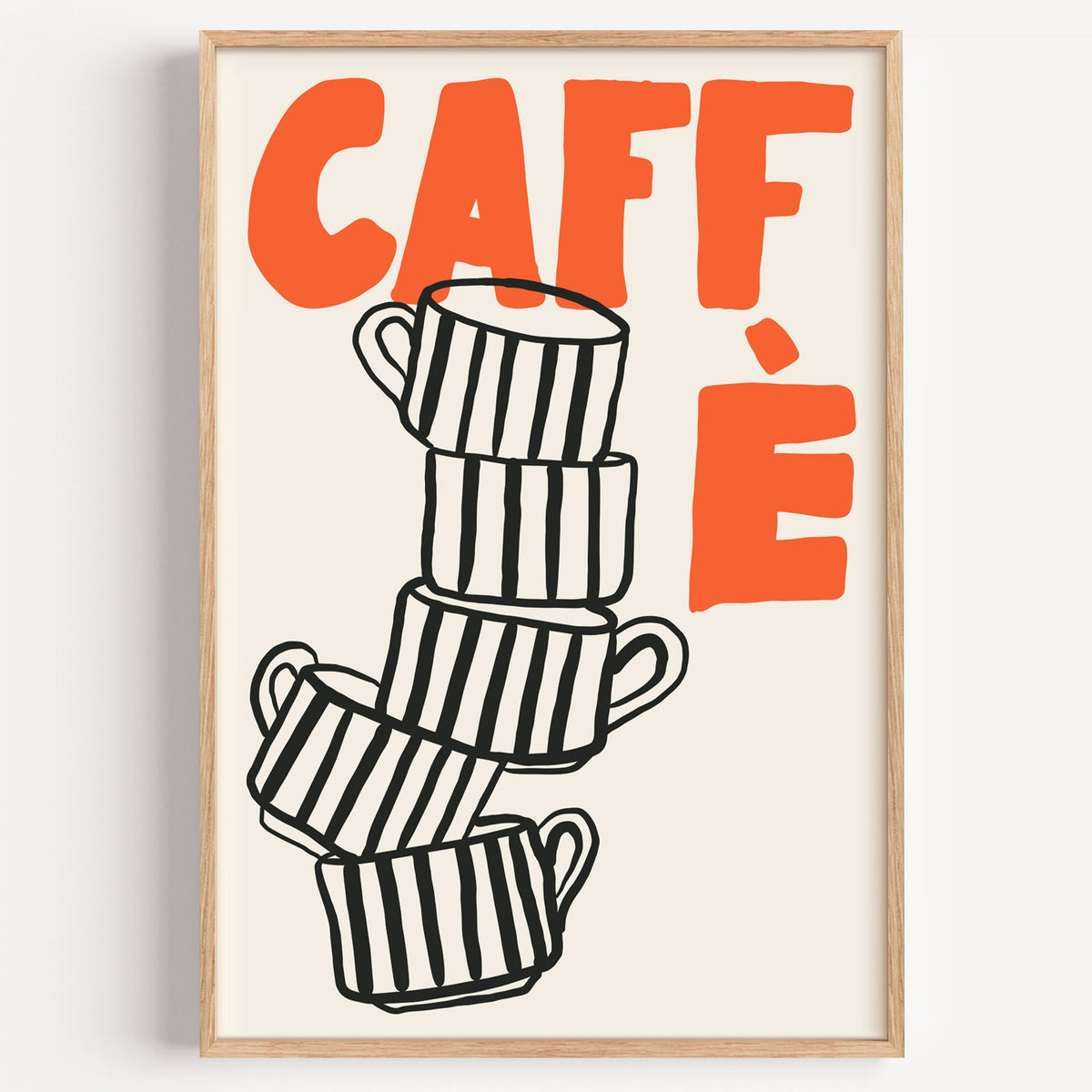 Stacked espresso cups print in a light oak frame on a plain white wall