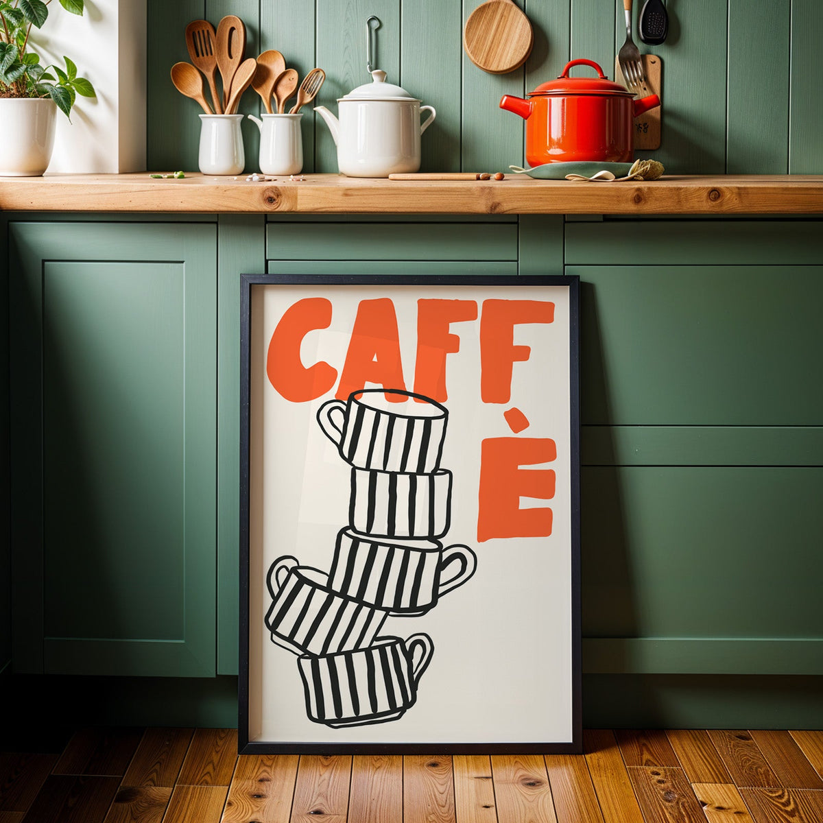 Stacked espresso cups print in a black frame against sage green kitchen cabinets