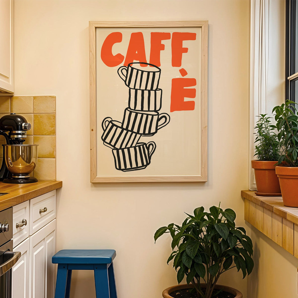 Stacked espresso cups print in a wood frame on a yellow tiled kitchen wall