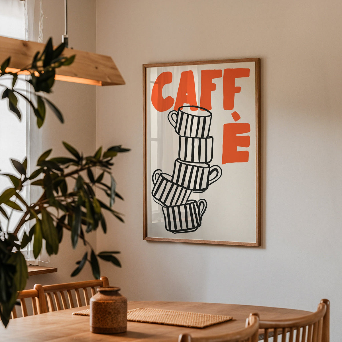 Stacked espresso cups print in a walnut frame above a dining table by an olive tree