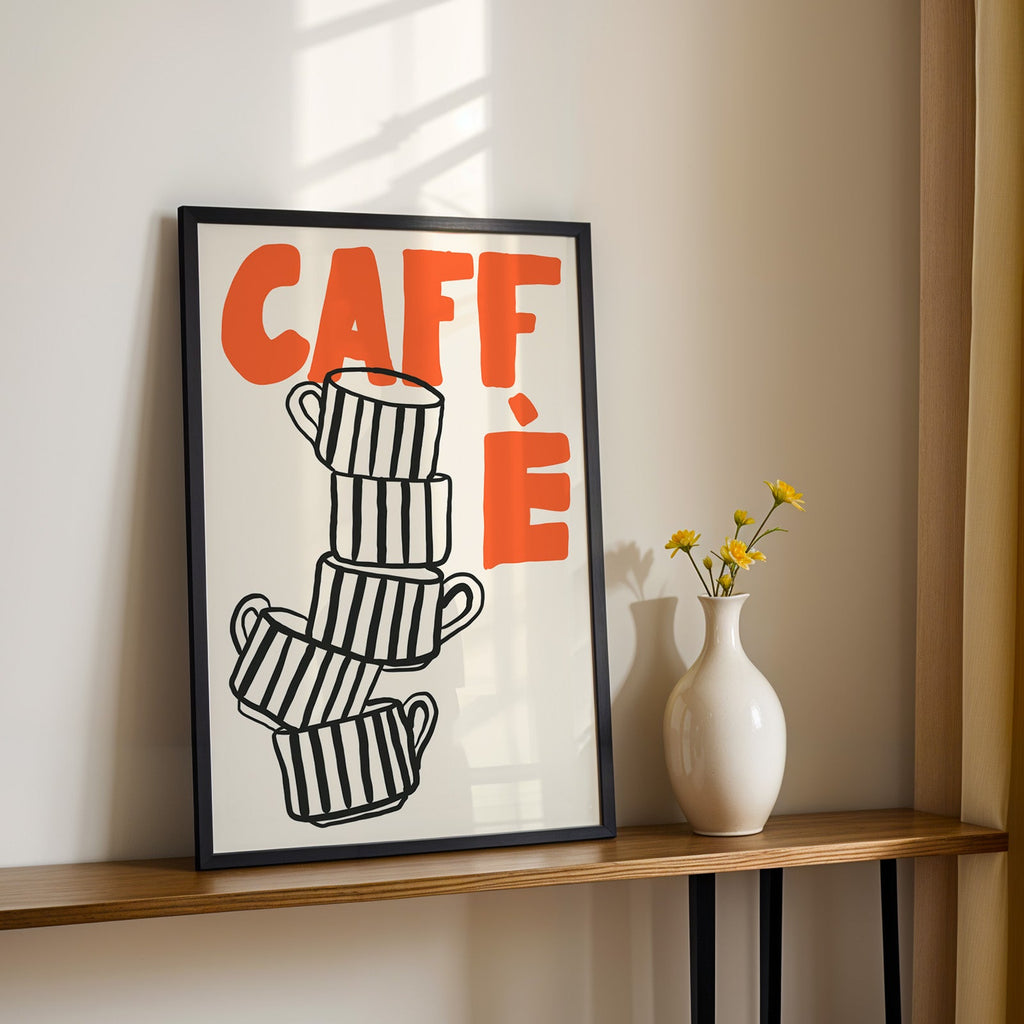 Stacked espresso cups print in a black frame on a console table with yellow daisies