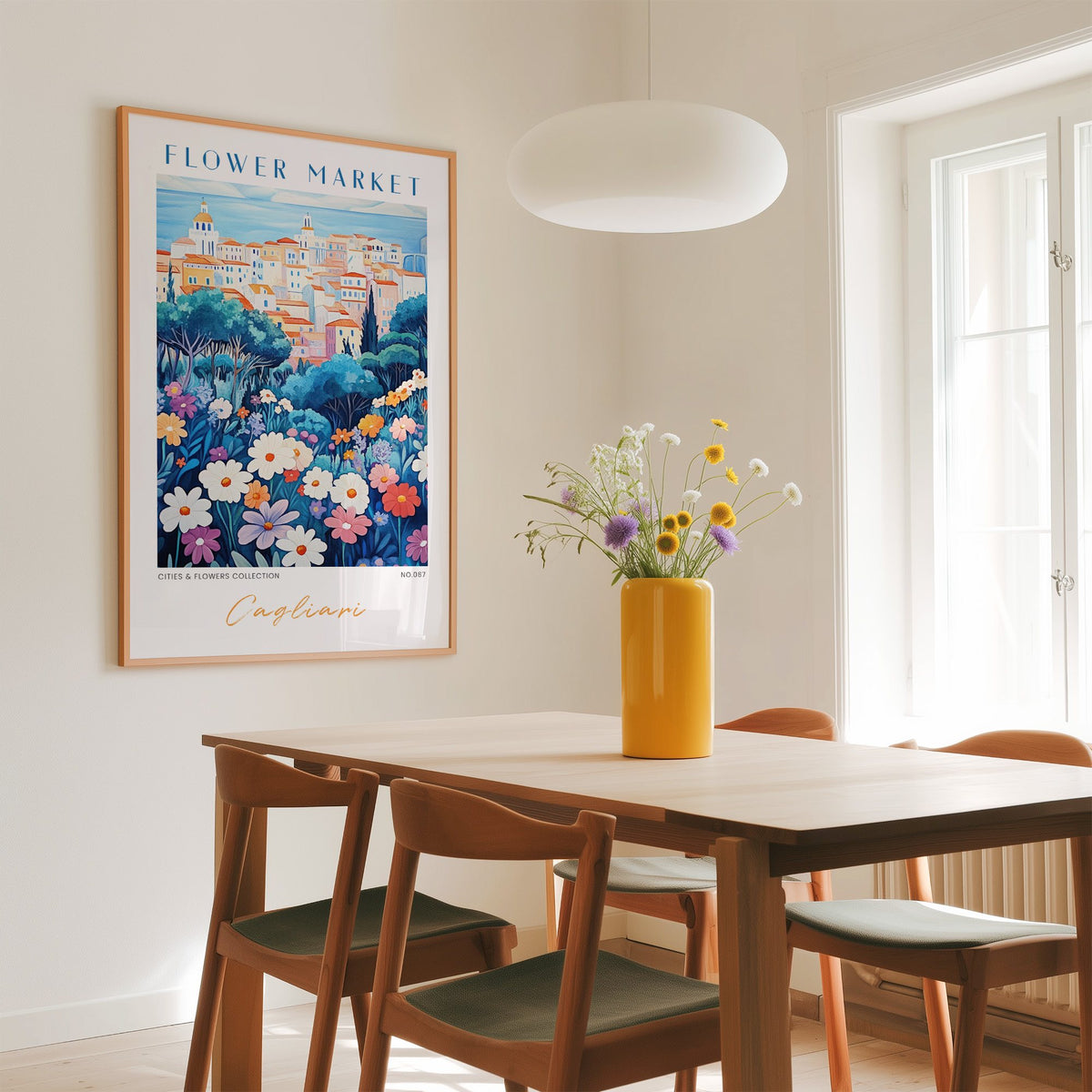Cagliari flower market print in an oak frame above a dining table with a yellow vase and white pendant light