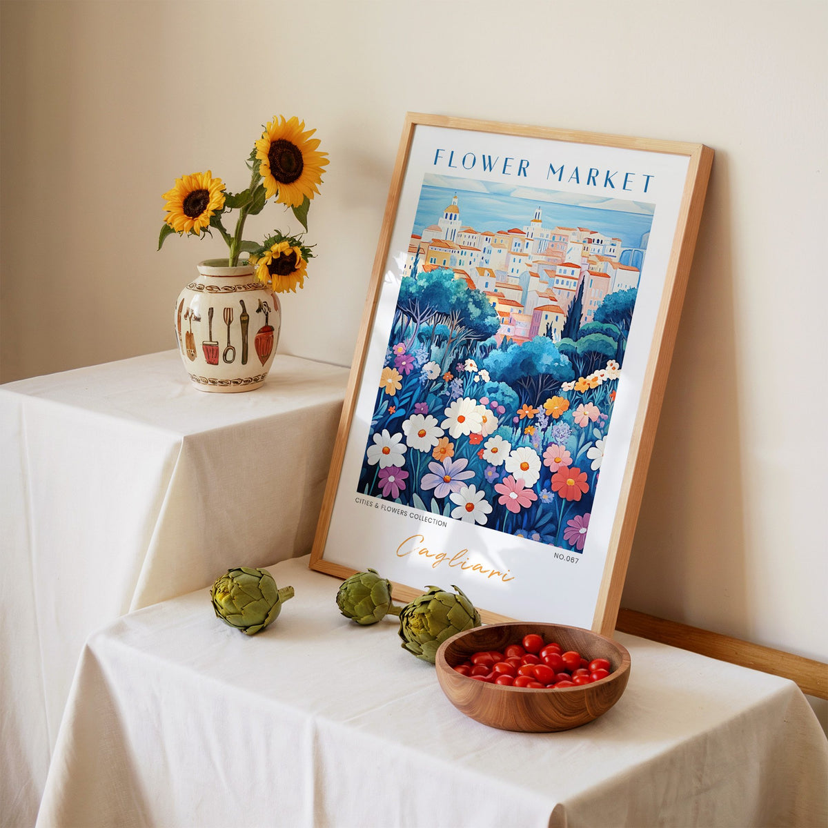Cagliari flower market print in an oak frame leaning on a linen-draped table beside a vase of sunflowers