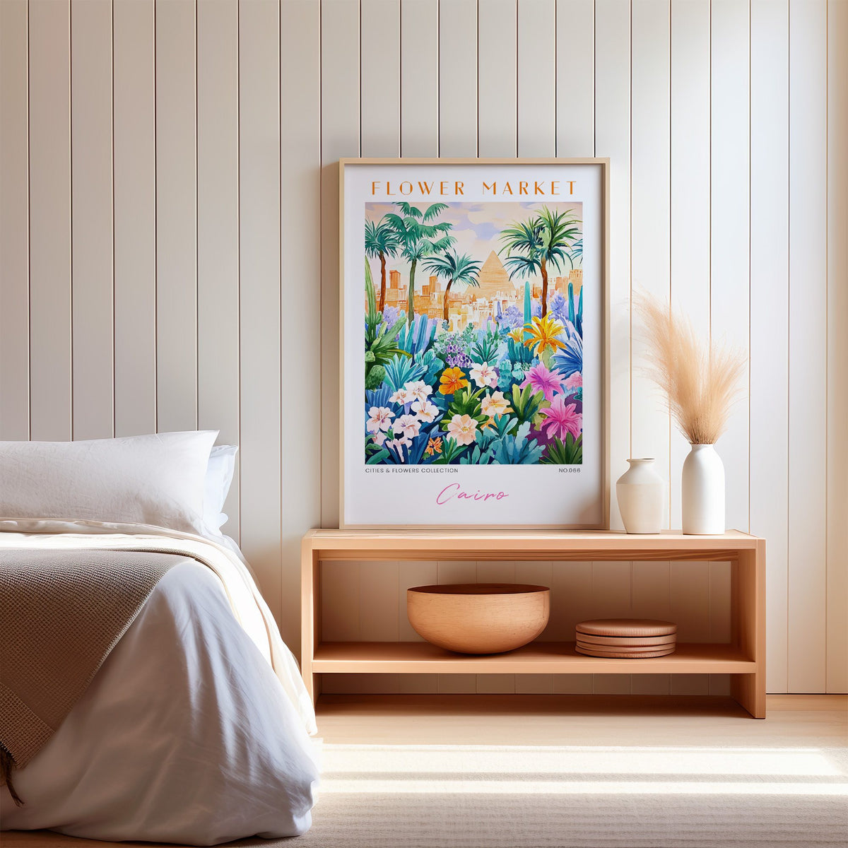 Cairo flower market print in an oak frame on a wood bench against a white shiplap bedroom wall with pampas grass