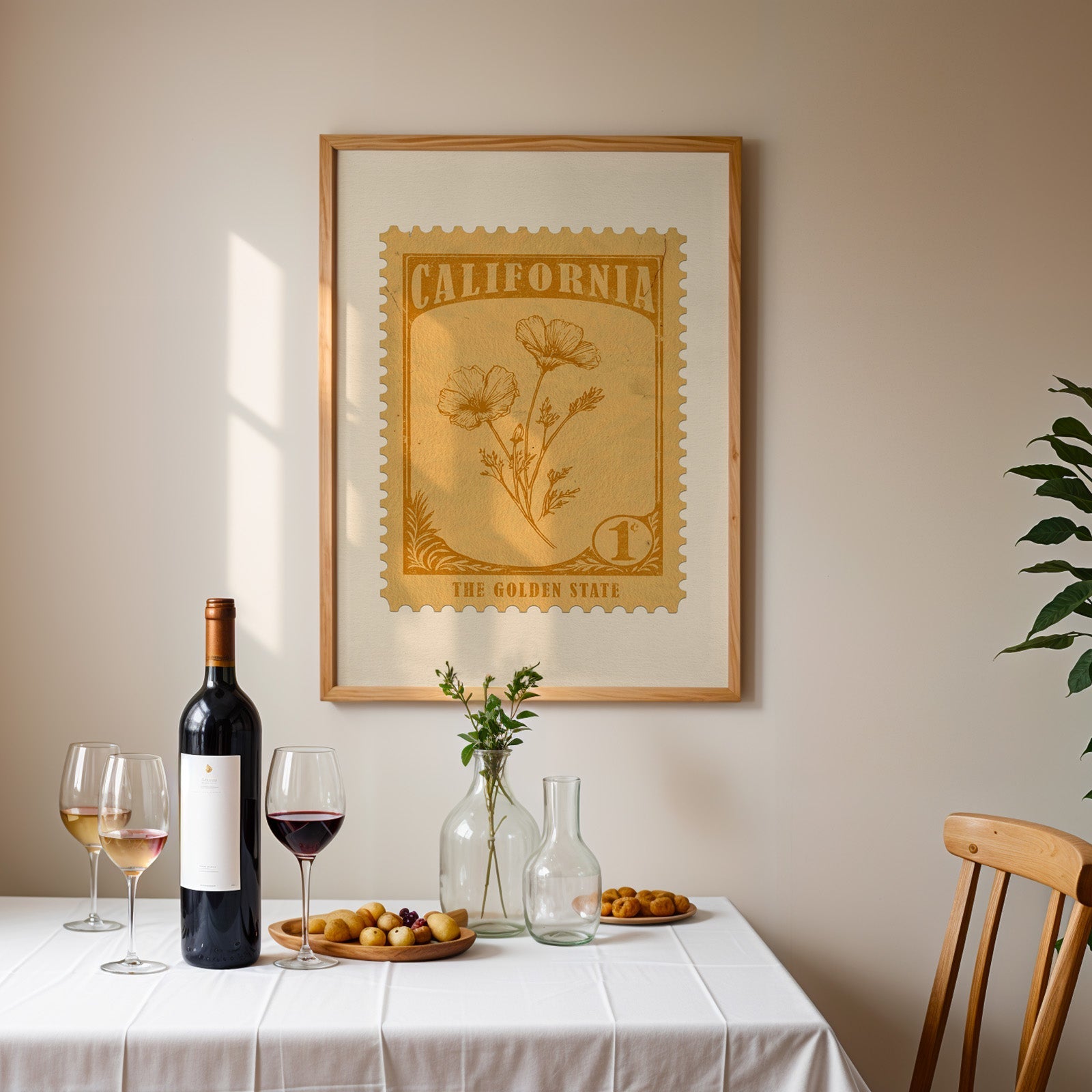 California stamp print framed on the wall above a dining table set with wine, glasses and a dish of olives