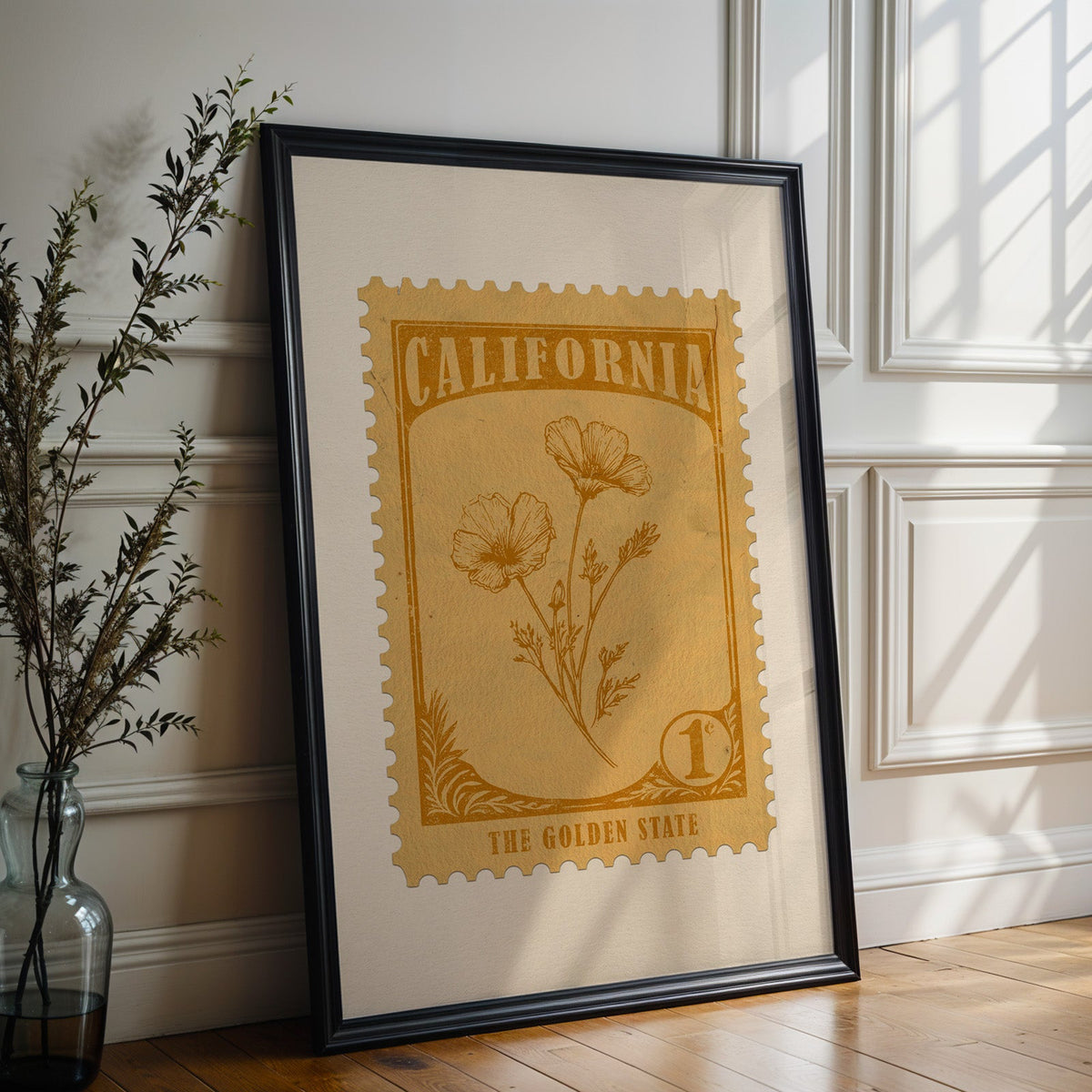 California state flower print in a black frame leaning against a white panelled wall beside olive branches