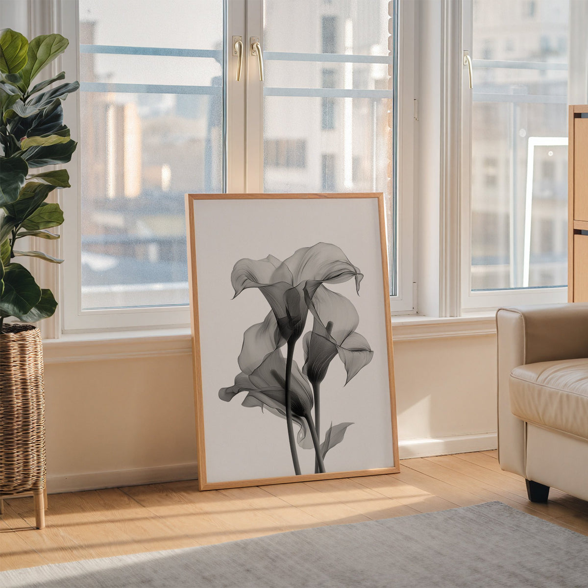 Translucent calla lily X-ray flowers print in an oak frame leaning on the floor beside a fiddle leaf fig