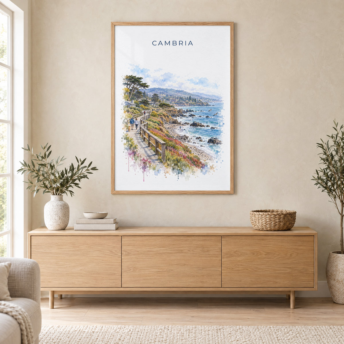 Cambria, California watercolor print in an oak frame above a light wood sideboard in a Scandinavian living room