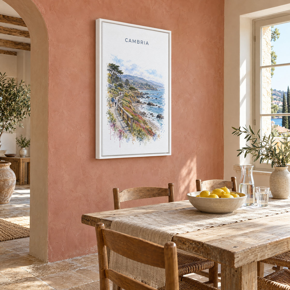 Cambria, California watercolor print as a white floater canvas on a terracotta wall above a rustic dining table