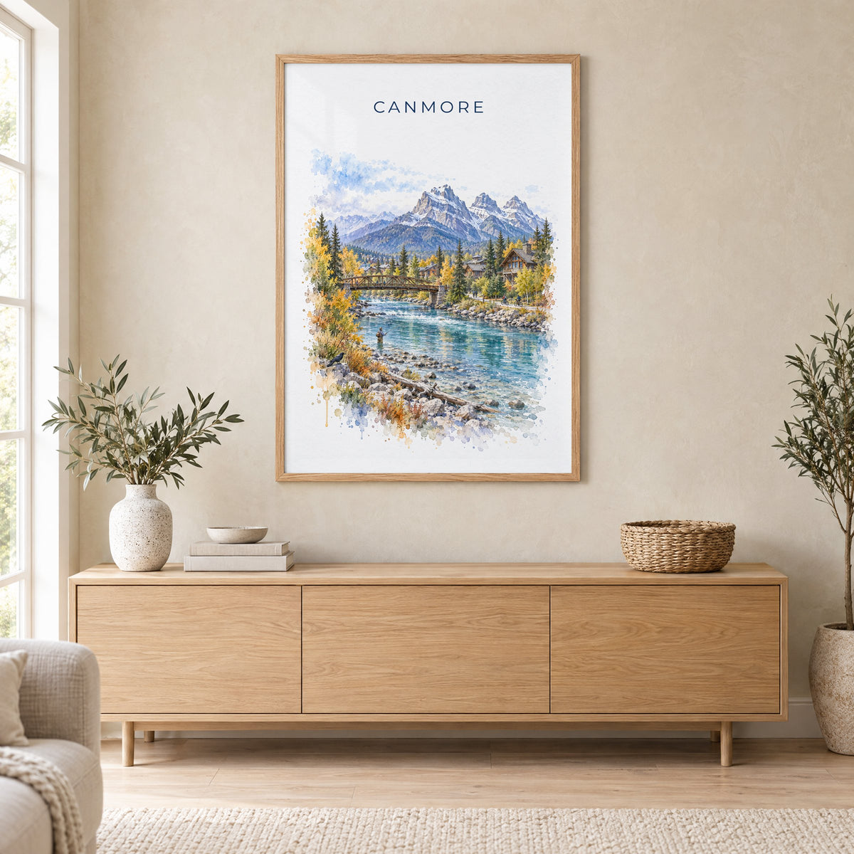 Canmore watercolor print in an oak frame above a light wood sideboard in a Scandinavian living room