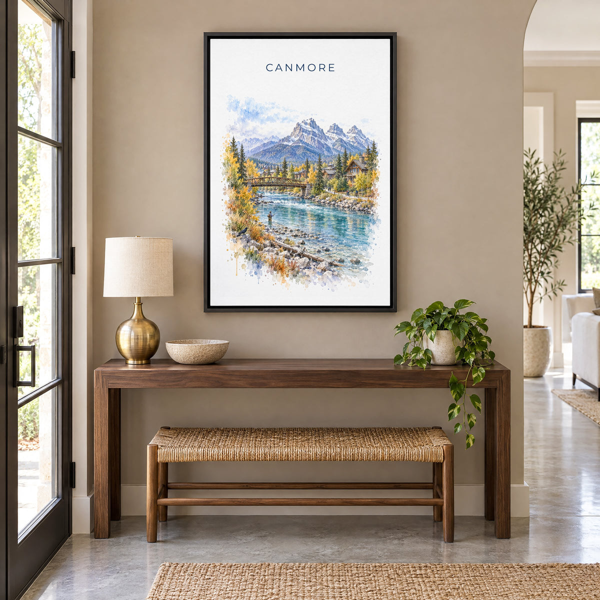 Canmore watercolor print as a black floater canvas above a walnut console and woven bench in an entryway
