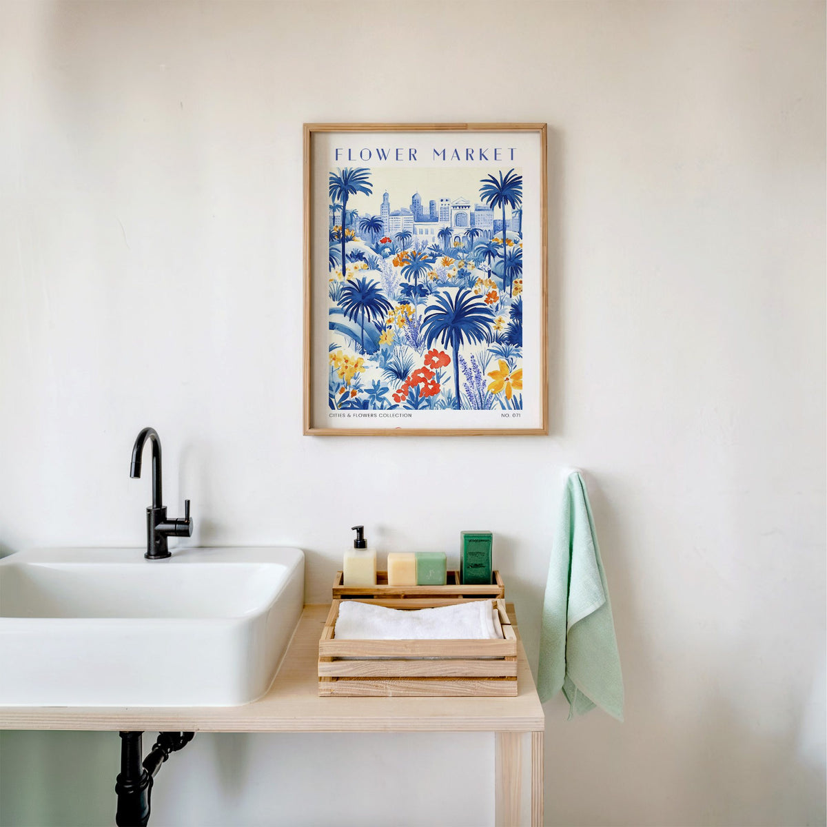 Cannes flower market print in an oak frame above a white bathroom sink with folded towels