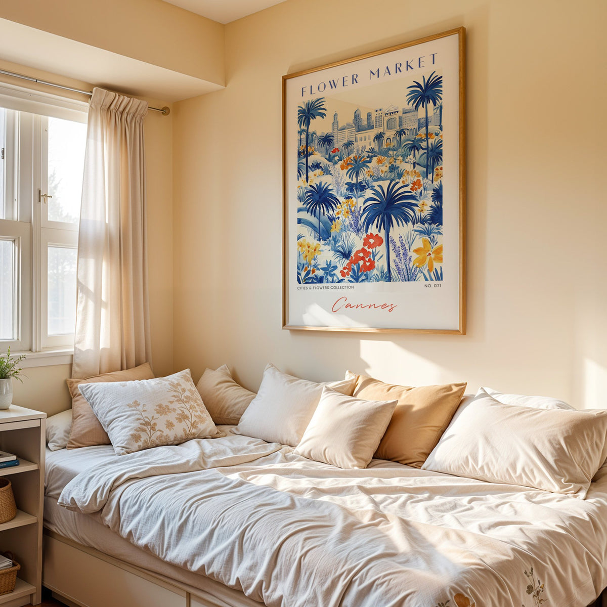 Cannes flower market print in an oak frame above a cream daybed in a sunny bedroom