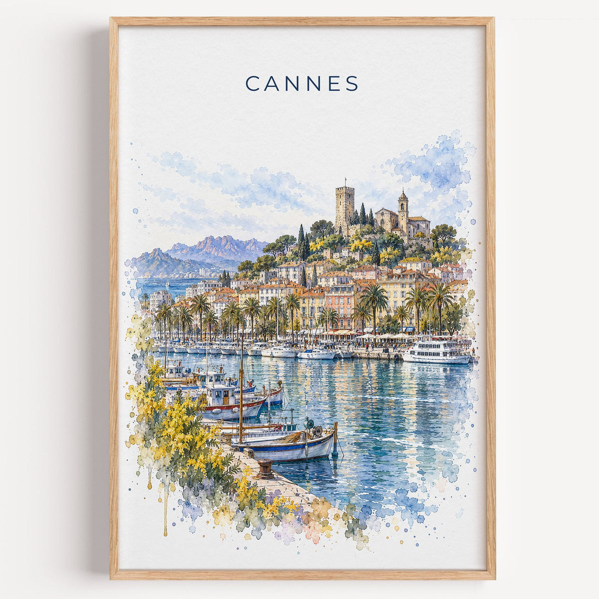 Cannes watercolor print in a light oak frame on a plain white wall