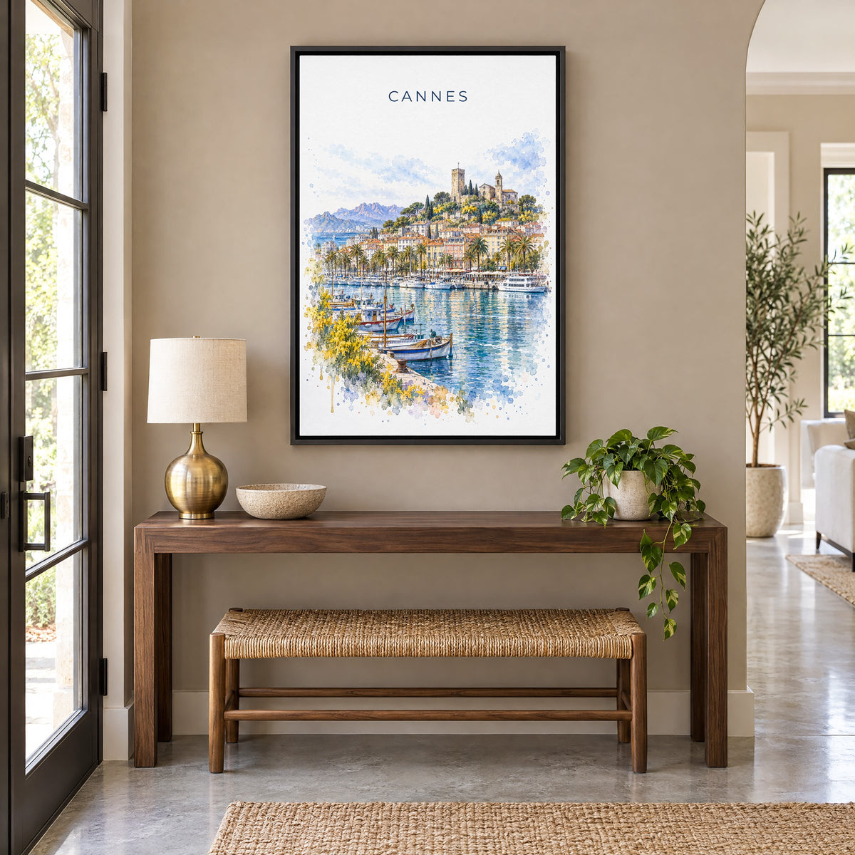 Cannes watercolor print as a black floater canvas above a walnut console and woven bench in an entryway