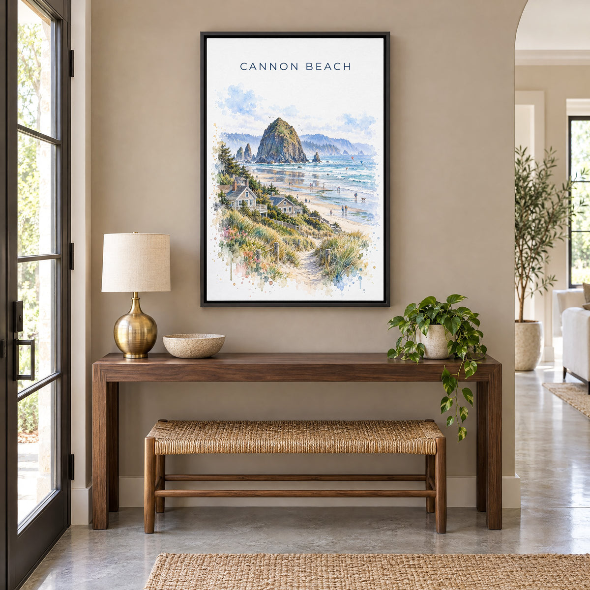 Cannon Beach watercolor print as a black floater canvas above a walnut console and woven bench in an entryway