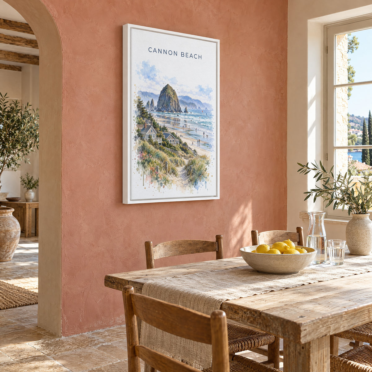 Cannon Beach watercolor print as a white floater canvas on a terracotta wall above a rustic dining table