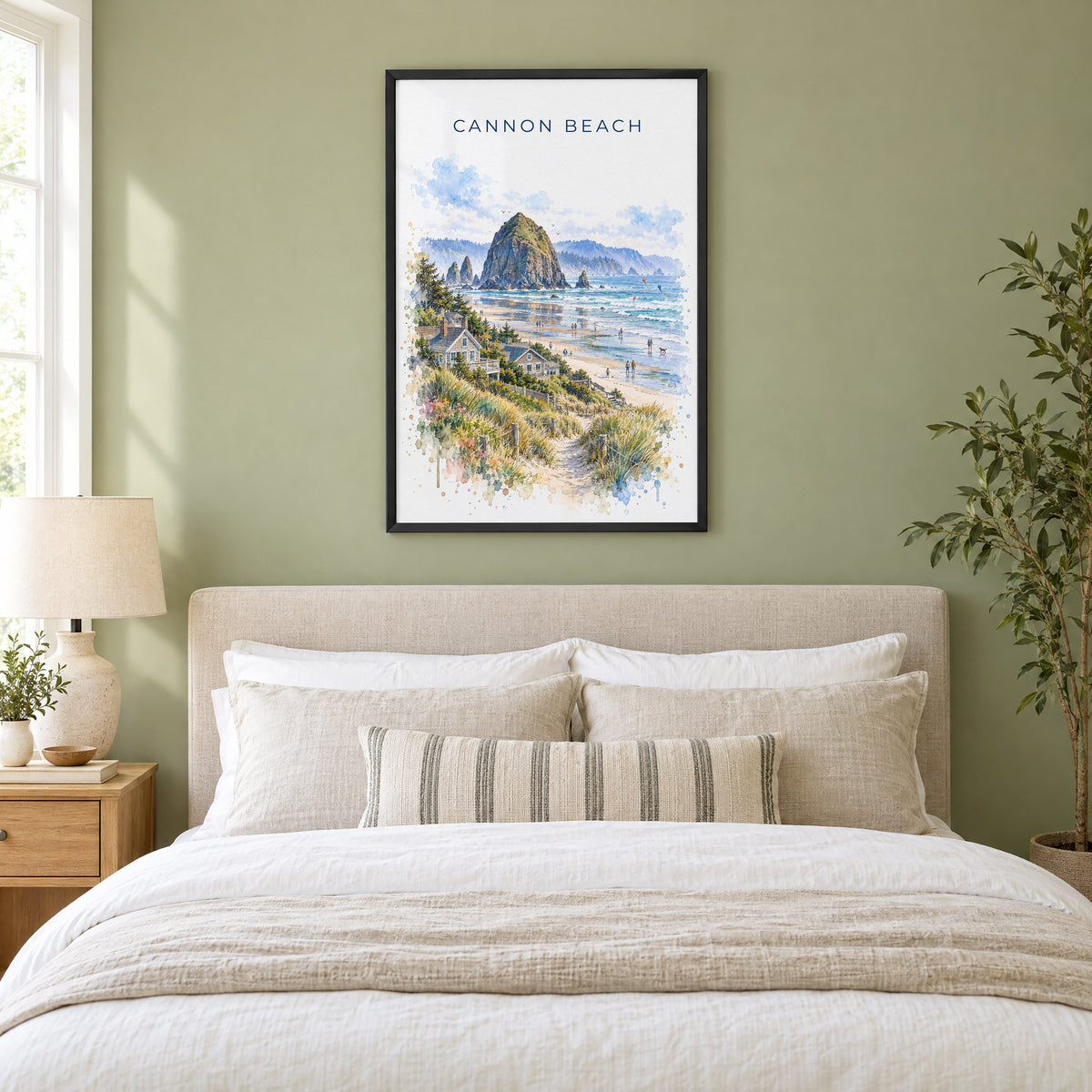 Cannon Beach watercolor print in a black frame above an upholstered headboard in a sage green bedroom