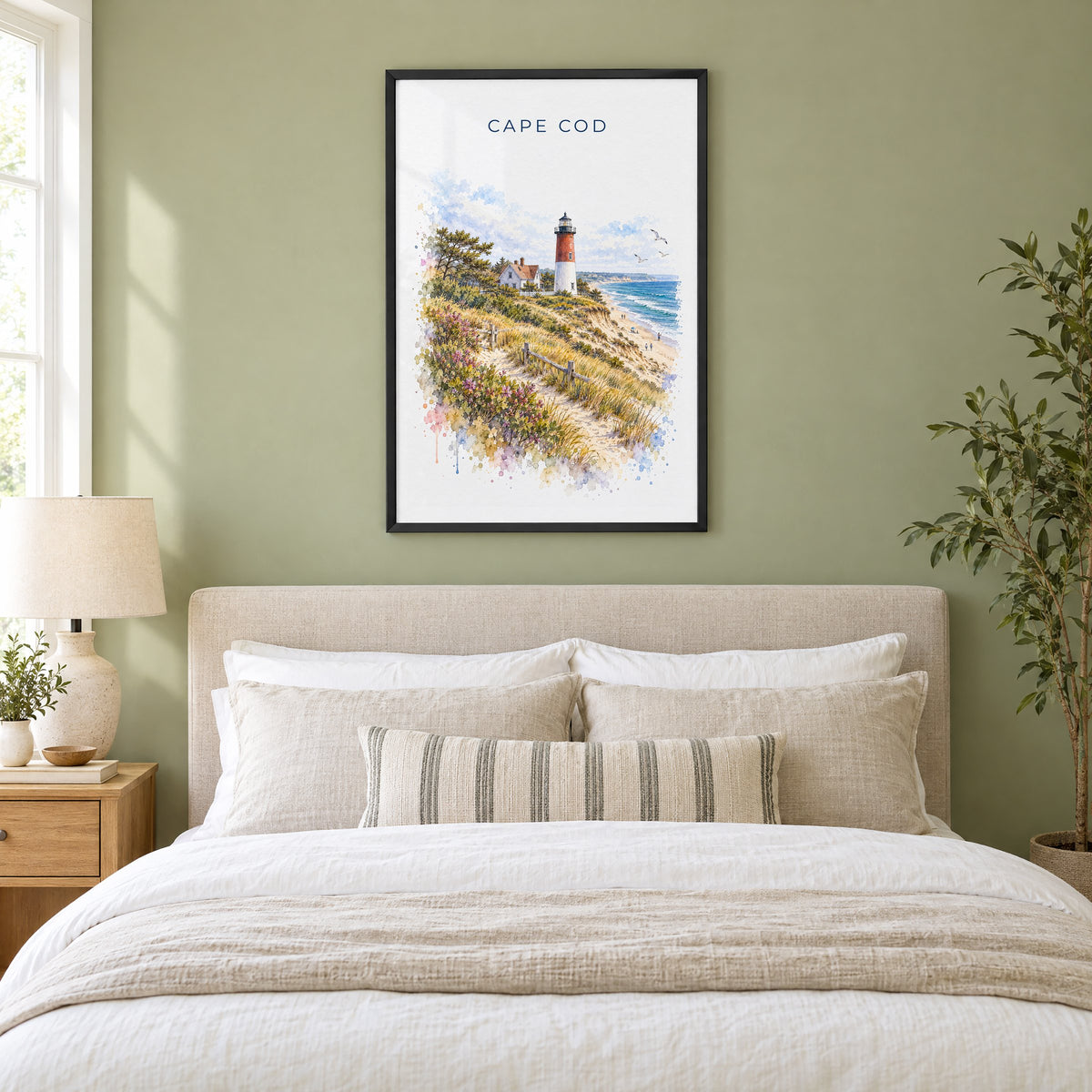 Cape Cod National Seashore watercolor print in a black frame above an upholstered headboard in a sage green bedroom