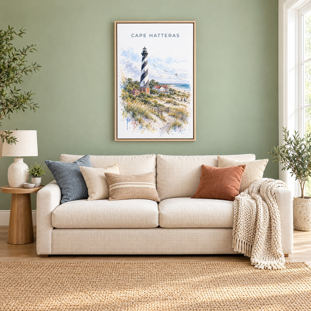 Cape Hatteras watercolor print as a natural floater canvas above a cream linen sofa on a sage green wall