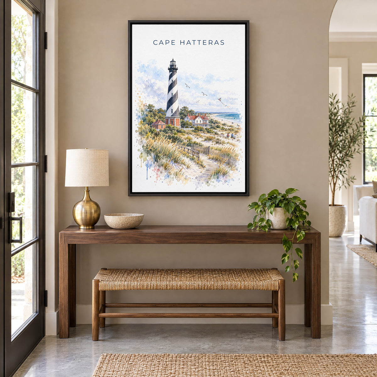 Cape Hatteras watercolor print as a black floater canvas above a walnut console and woven bench in an entryway