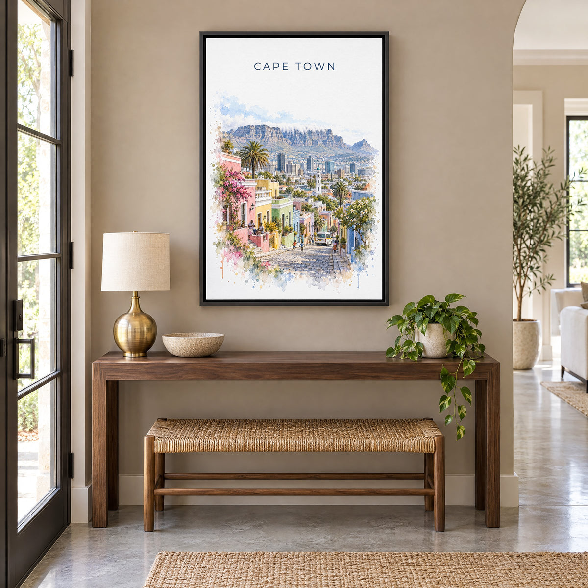 Cape Town watercolor print as a black floater canvas above a walnut console and woven bench in an entryway