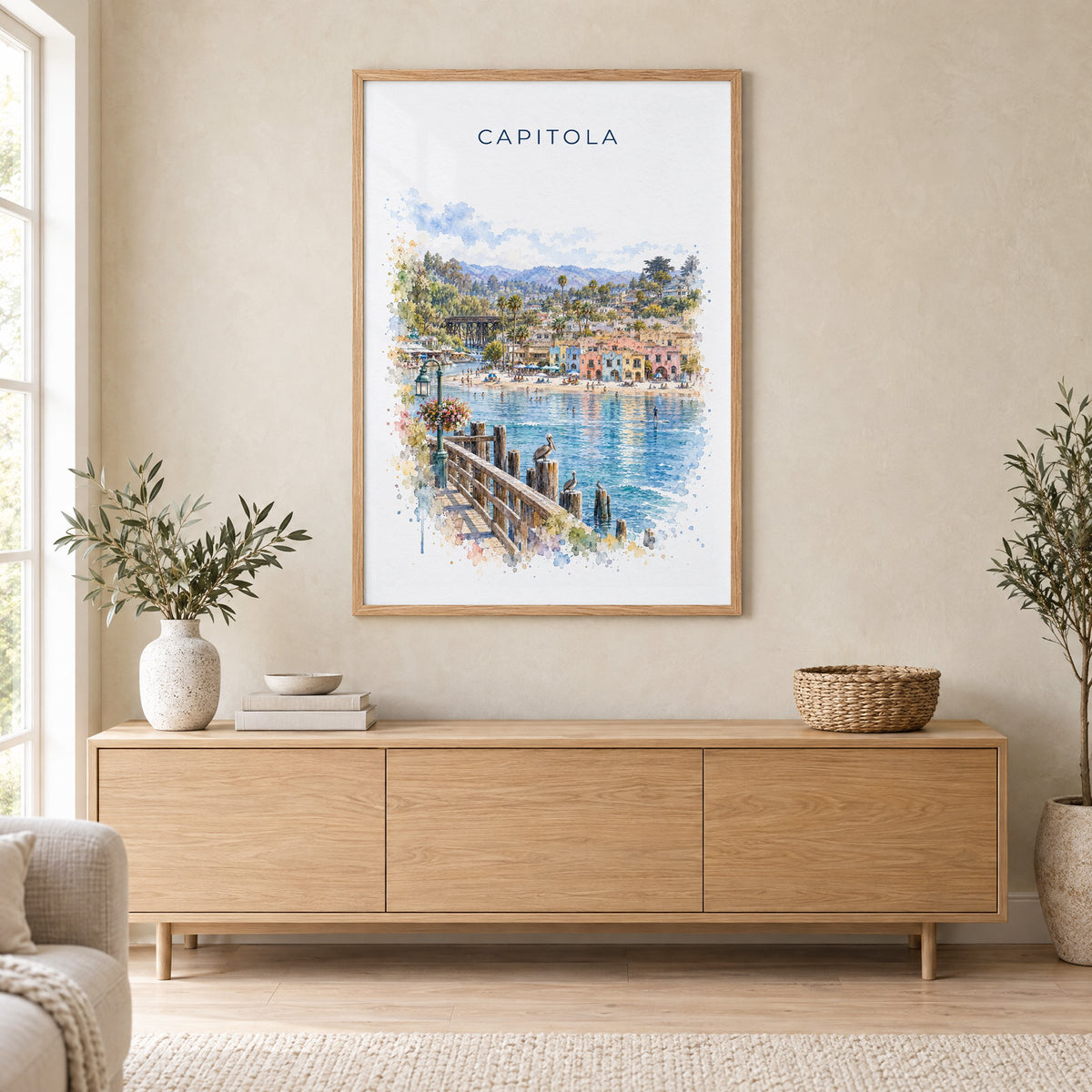 Capitola, California watercolor print in an oak frame above a light wood sideboard in a Scandinavian living room