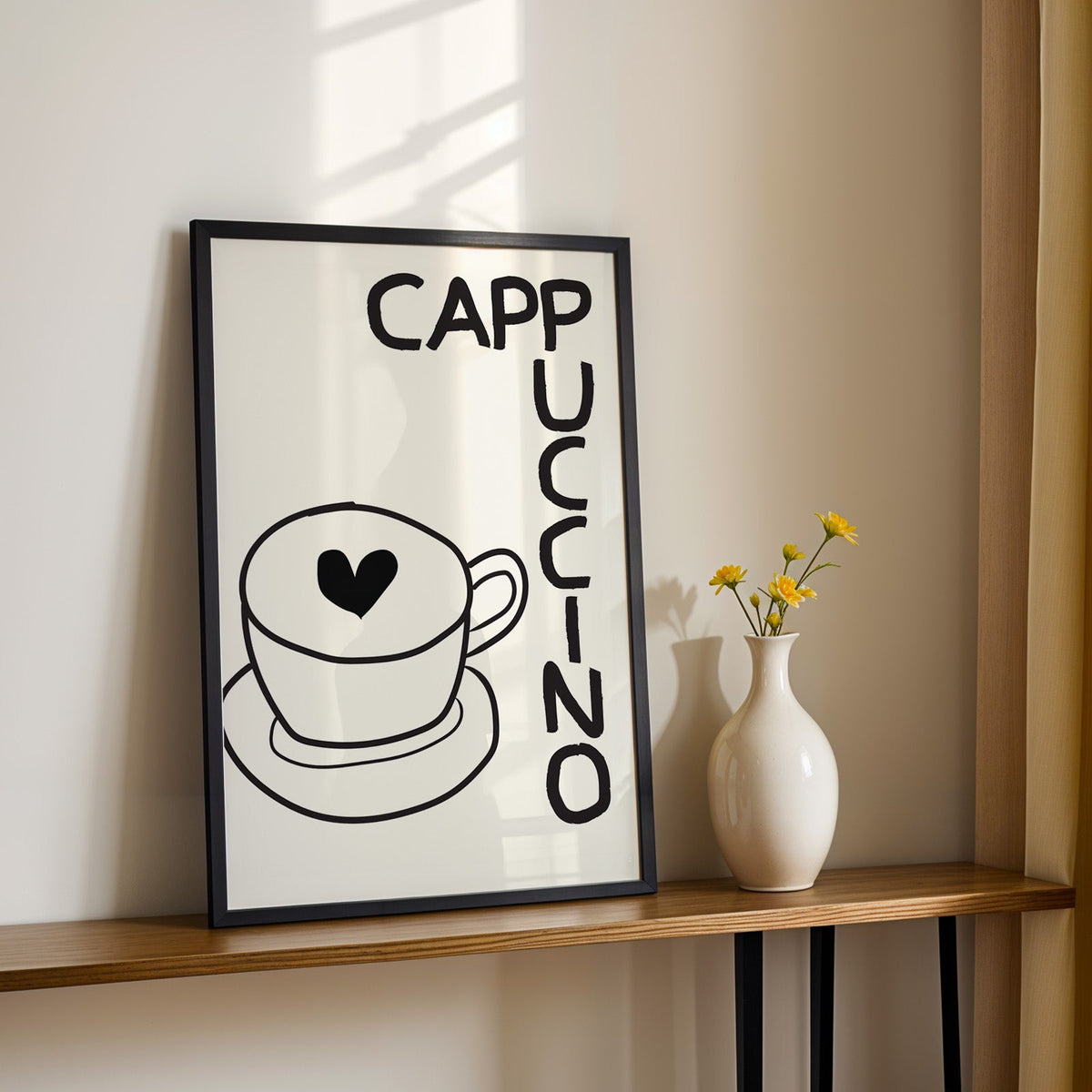 Cappuccino heart print in a black frame on a console table with yellow daisies