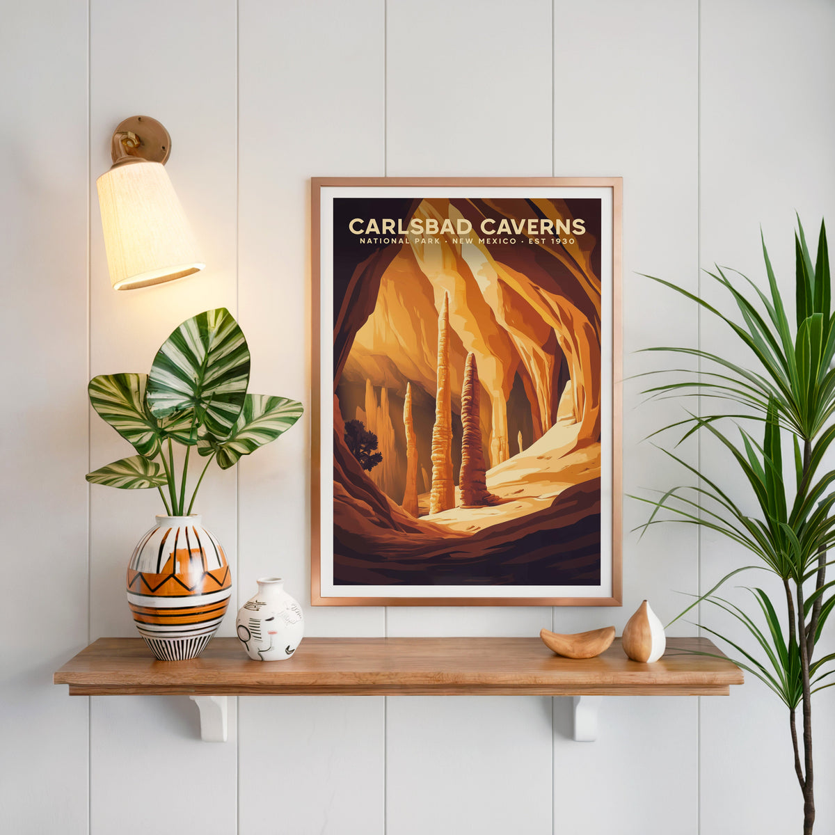 Carlsbad Caverns print in a copper frame above an oak shelf on white shiplap with a sconce