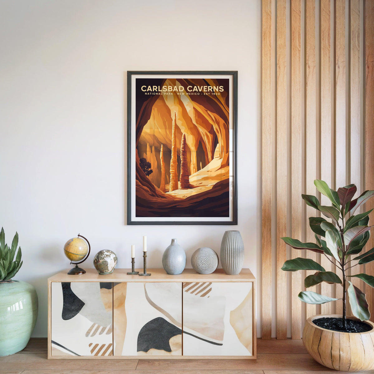 Carlsbad Caverns print in a black frame above a light wood sideboard with a globe and vases