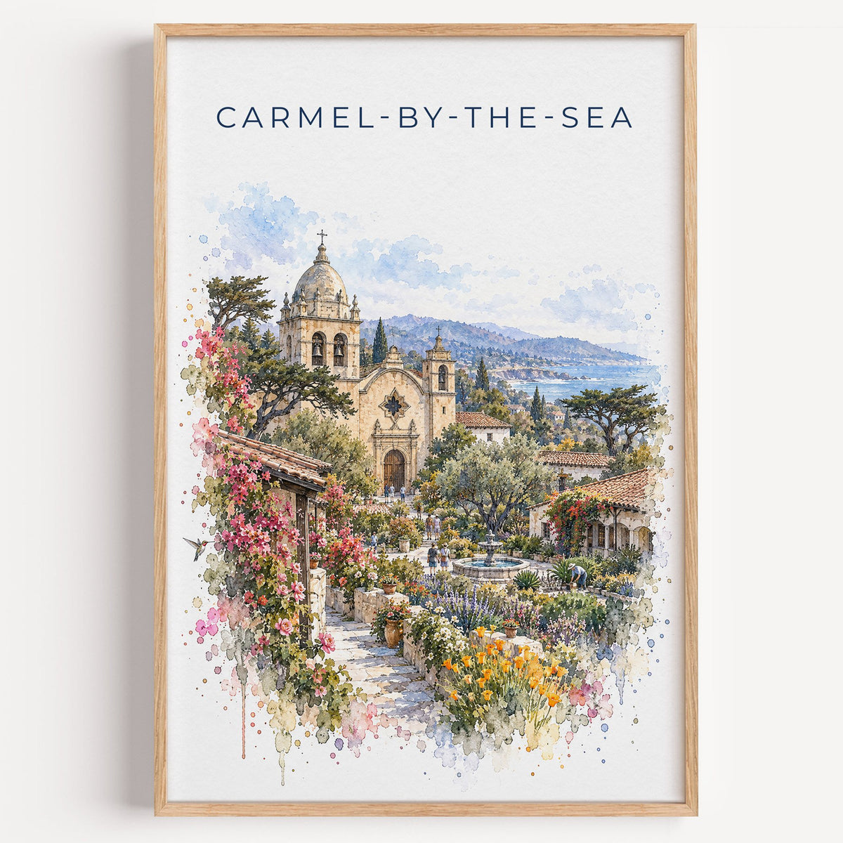 Carmel-by-the-Sea watercolor print in a light oak frame on a plain white wall