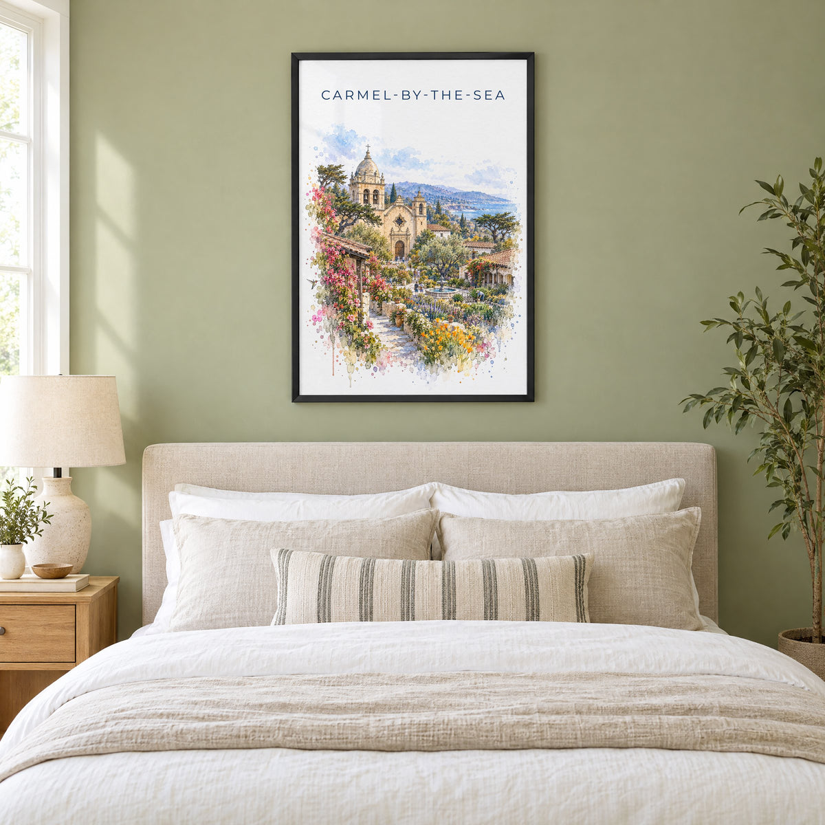 Carmel-by-the-Sea watercolor print in a black frame above an upholstered headboard in a sage green bedroom