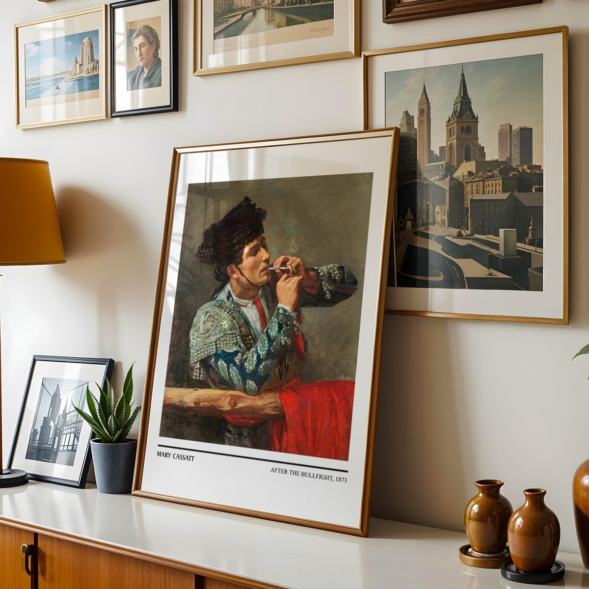 Teal and silver costume print shown in a gold frame leaning on a sideboard in a gallery wall