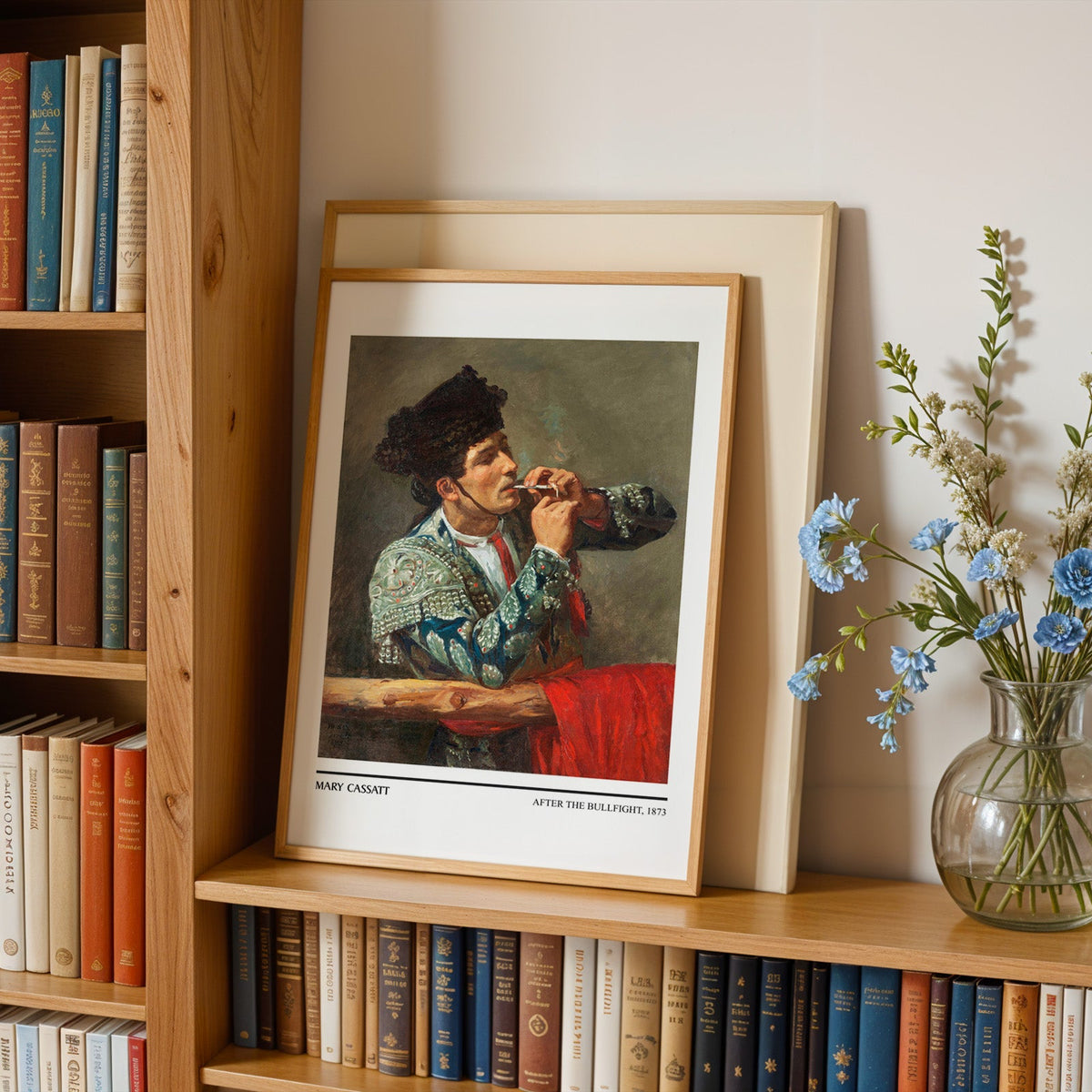 Seville matador print in an oak frame leaning on a bookshelf beside flowers