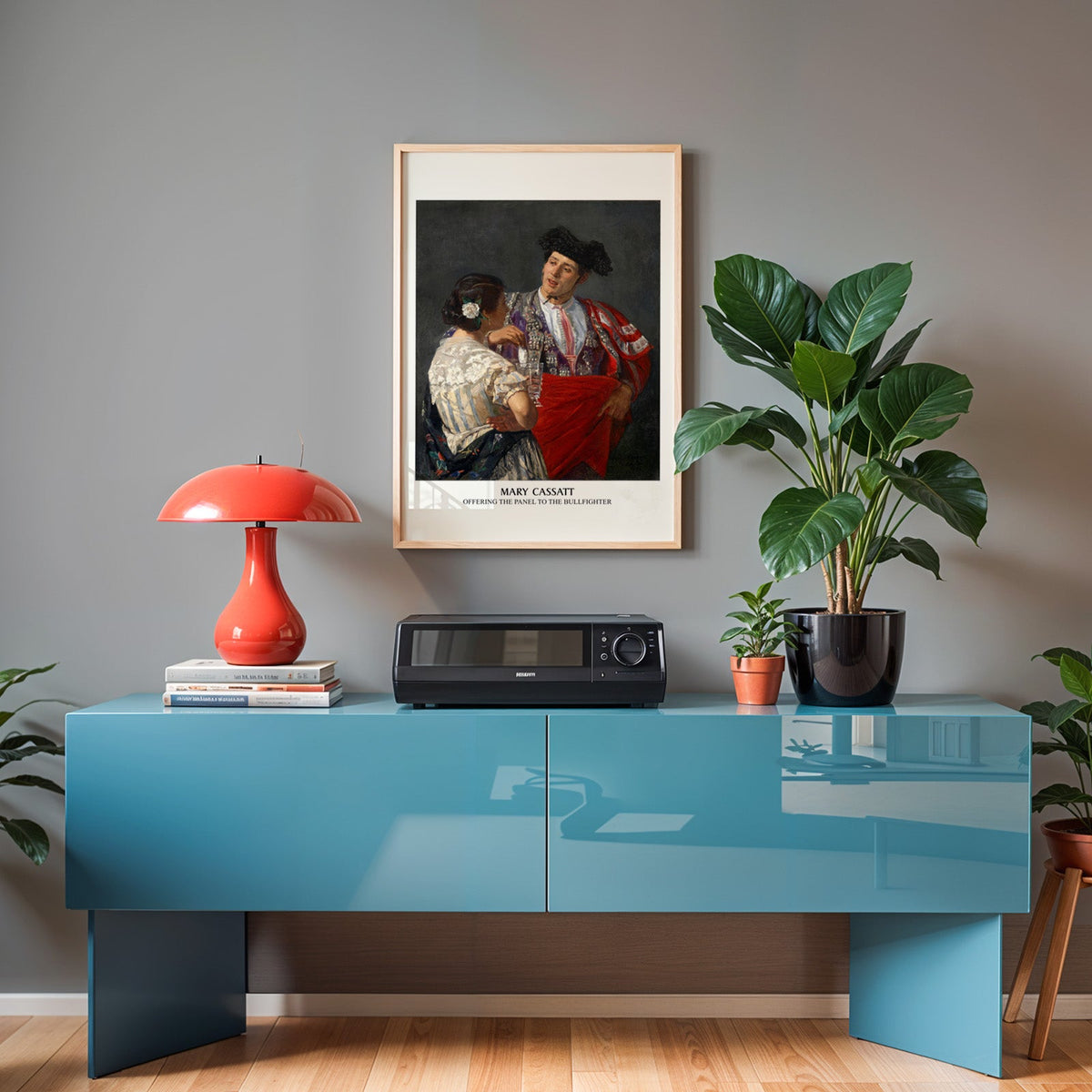 Cassatt print in an oak frame above a teal sideboard with a red lamp