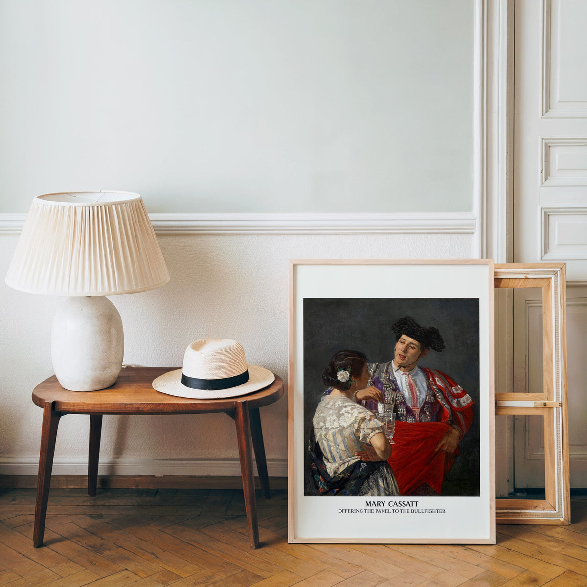 Impressionist figure poster in a light wood frame leaning by a bench and hat