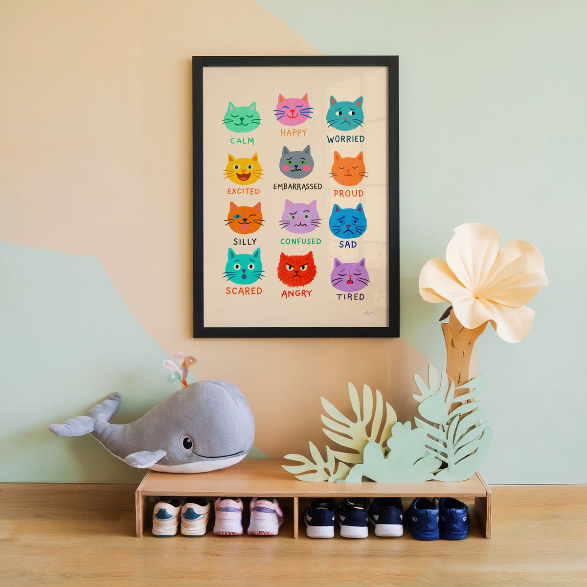 Colourful cat feelings chart nursery print in a black frame on a mint and peach wall above a whale plush