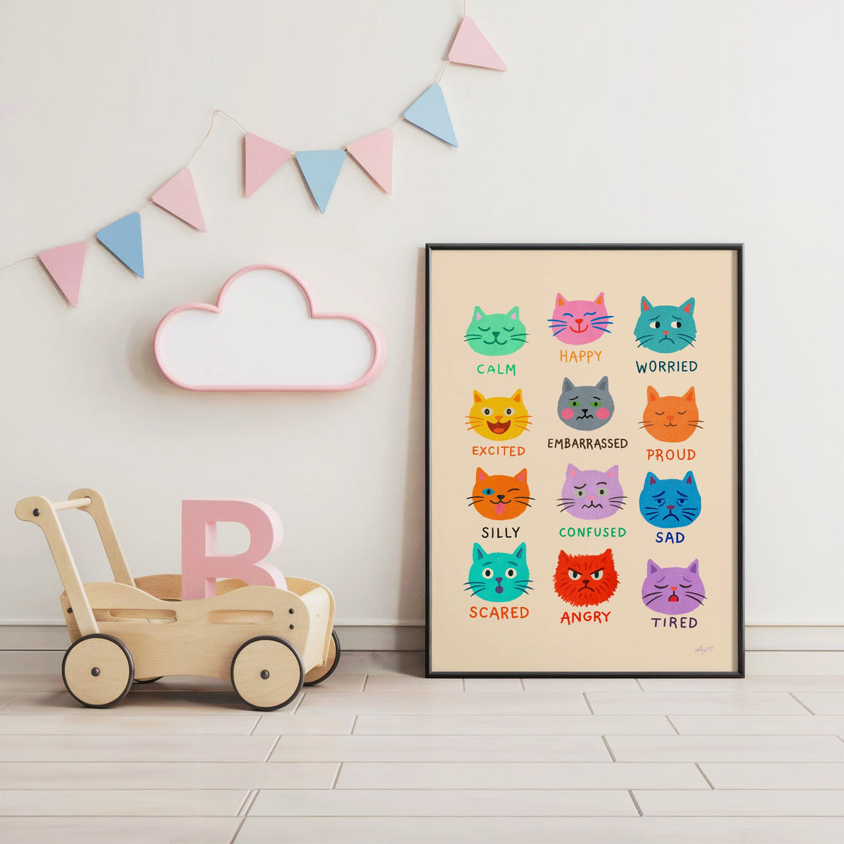 Colourful cat feelings chart nursery print in a black frame under pastel bunting by a wooden baby walker