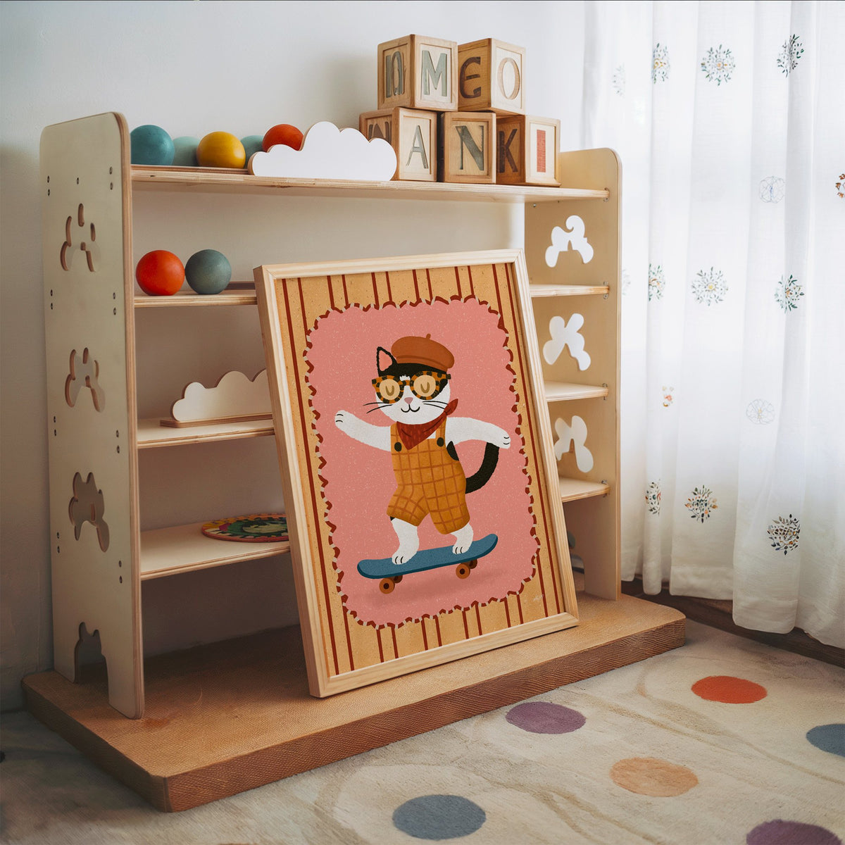 Black and white cat on skateboard nursery print in an oak frame leaning on a toy shelf with wooden letter blocks