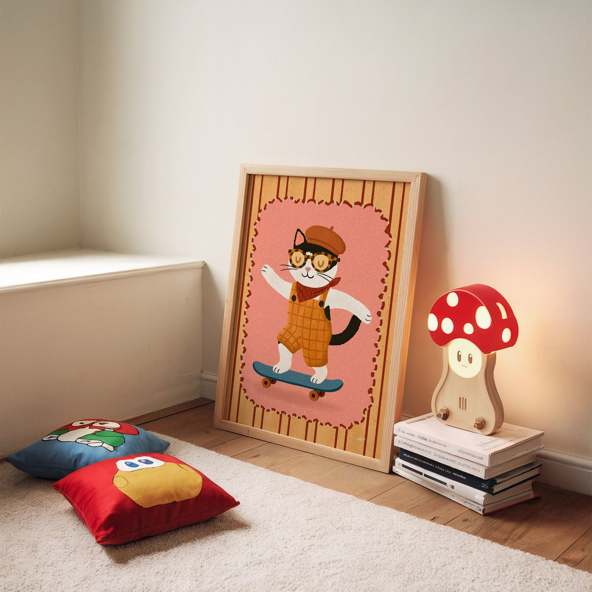 Black and white cat on skateboard nursery print in an oak frame leaning on a rug beside a mushroom lamp and floor cushions