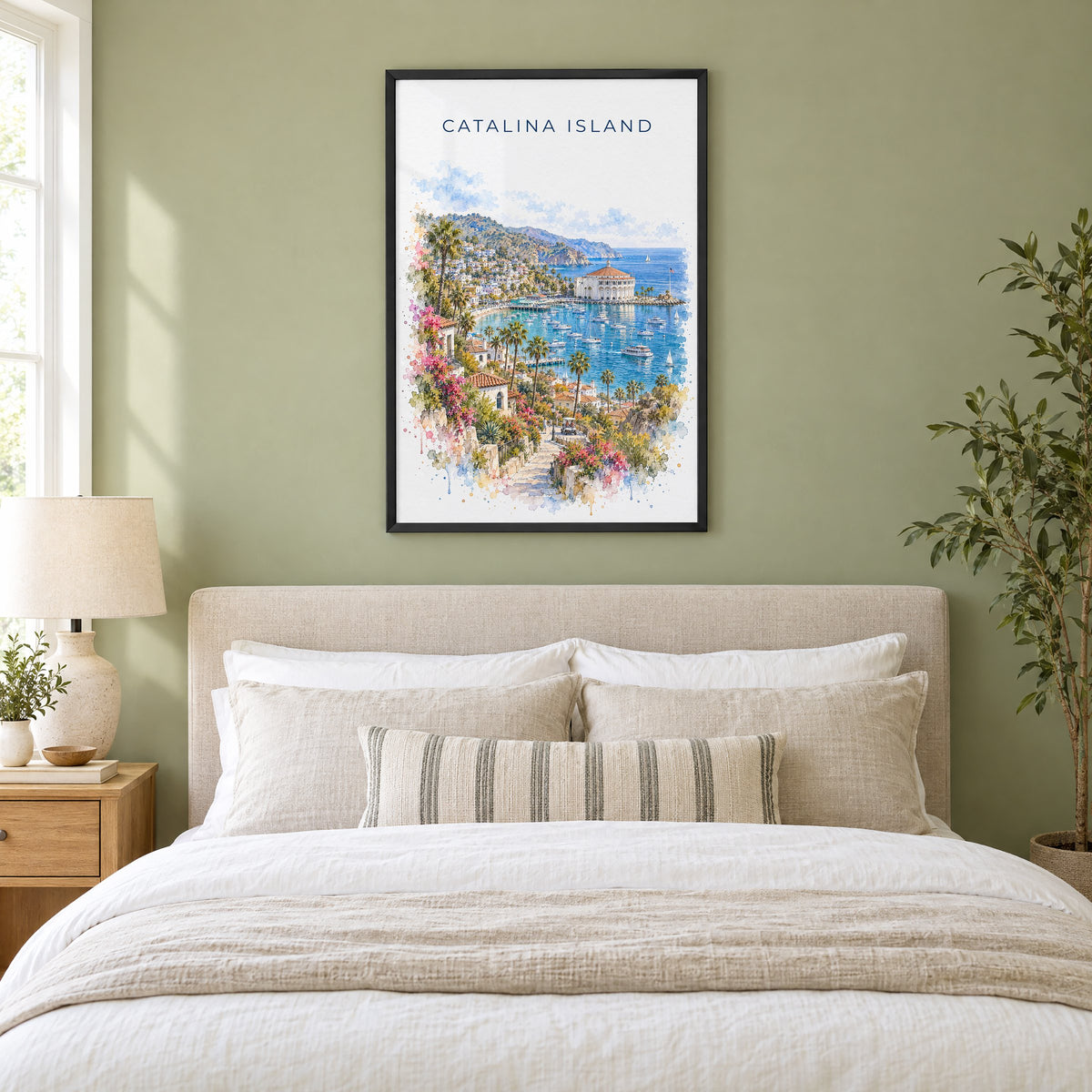 Catalina Island watercolor print in a black frame above an upholstered headboard in a sage green bedroom