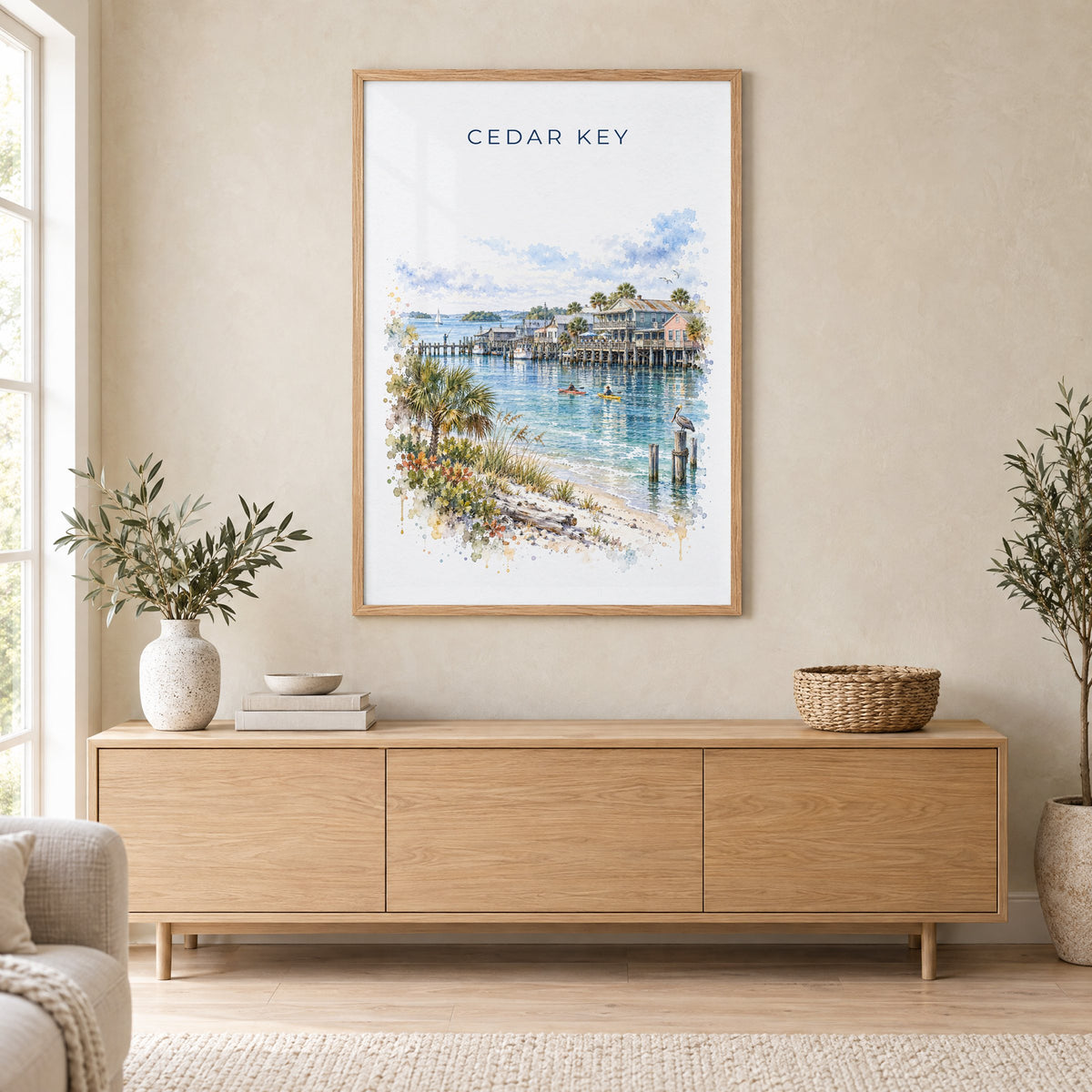 Cedar Key, Florida watercolor print in an oak frame above a light wood sideboard in a Scandinavian living room